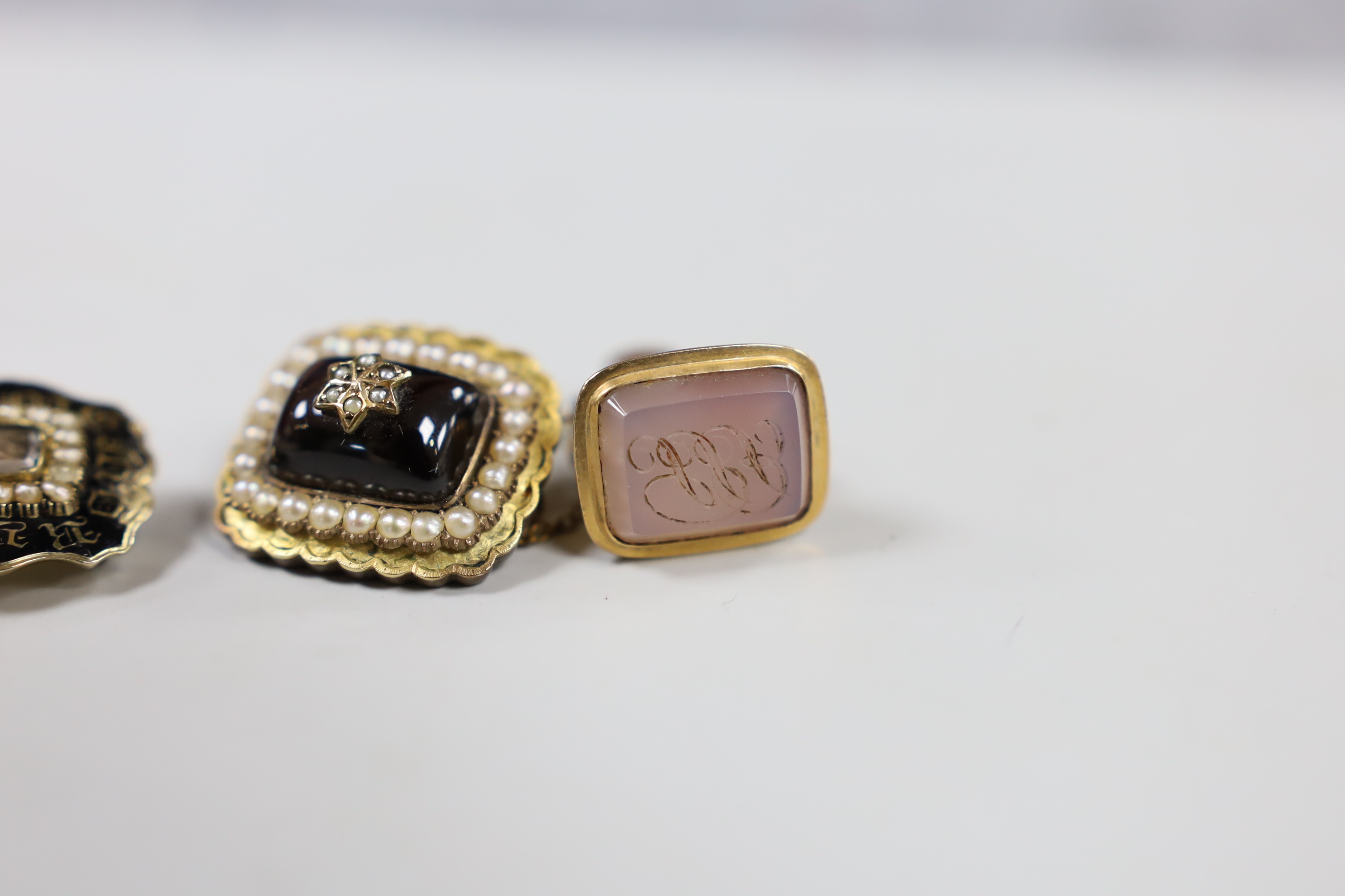 Two Victorian yellow metal and split pearl set mourning brooches, one with black enamel and inscribed ' JG aged 69 August 29th, 1840' and two Victorian yellow metal overlaid and chalcedony set fob seals.